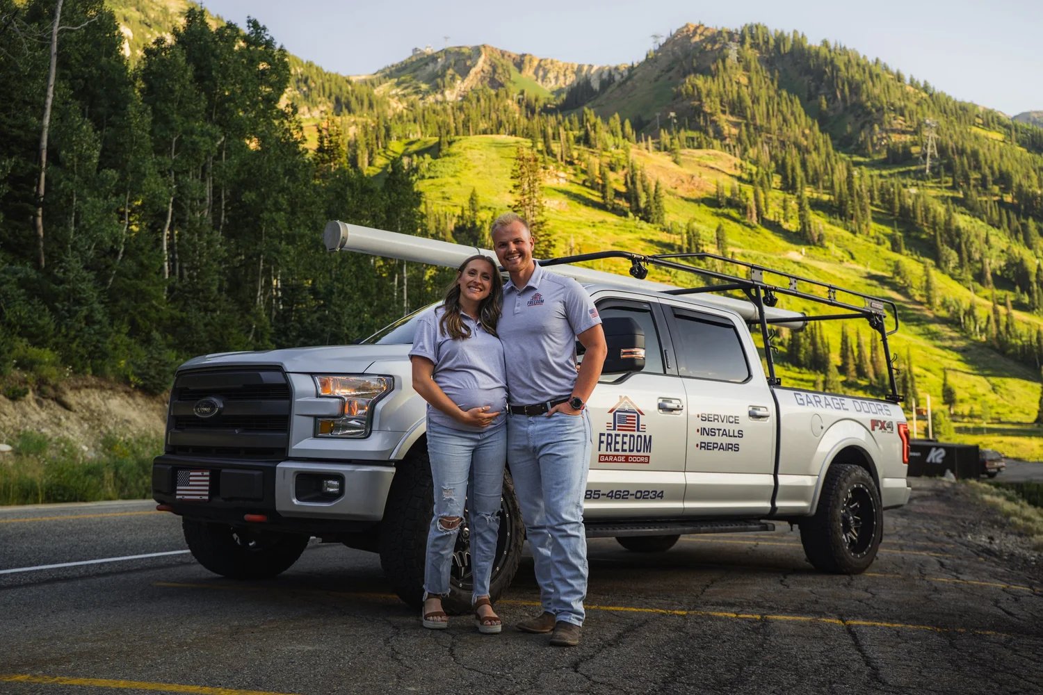 The owners of Freedom Garage Doors standing beside their service truck in the Utah mountains